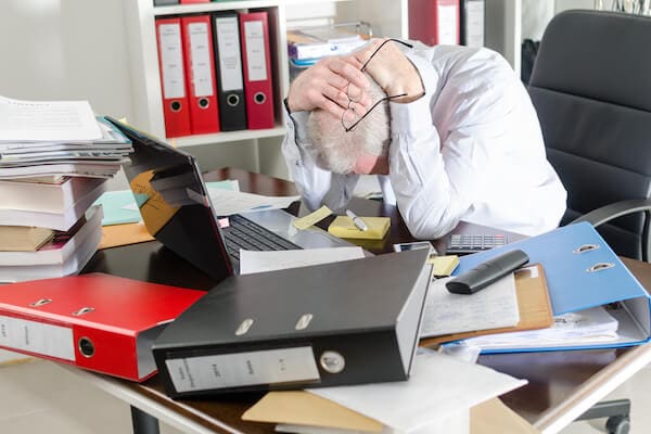 Man sitting at cluttered desk in need of workspace cleaning